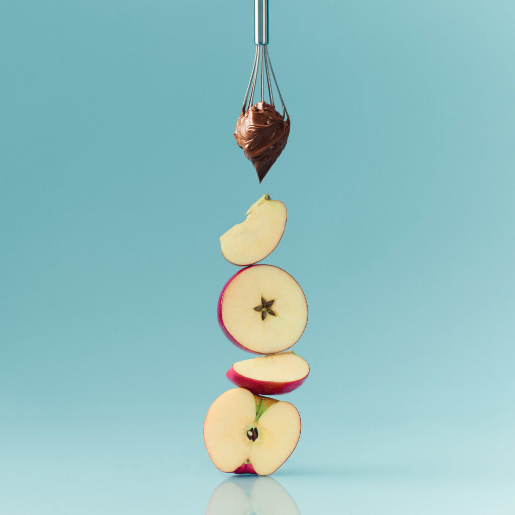 Stack of halved apples with a dollop of chocolate on a blue background