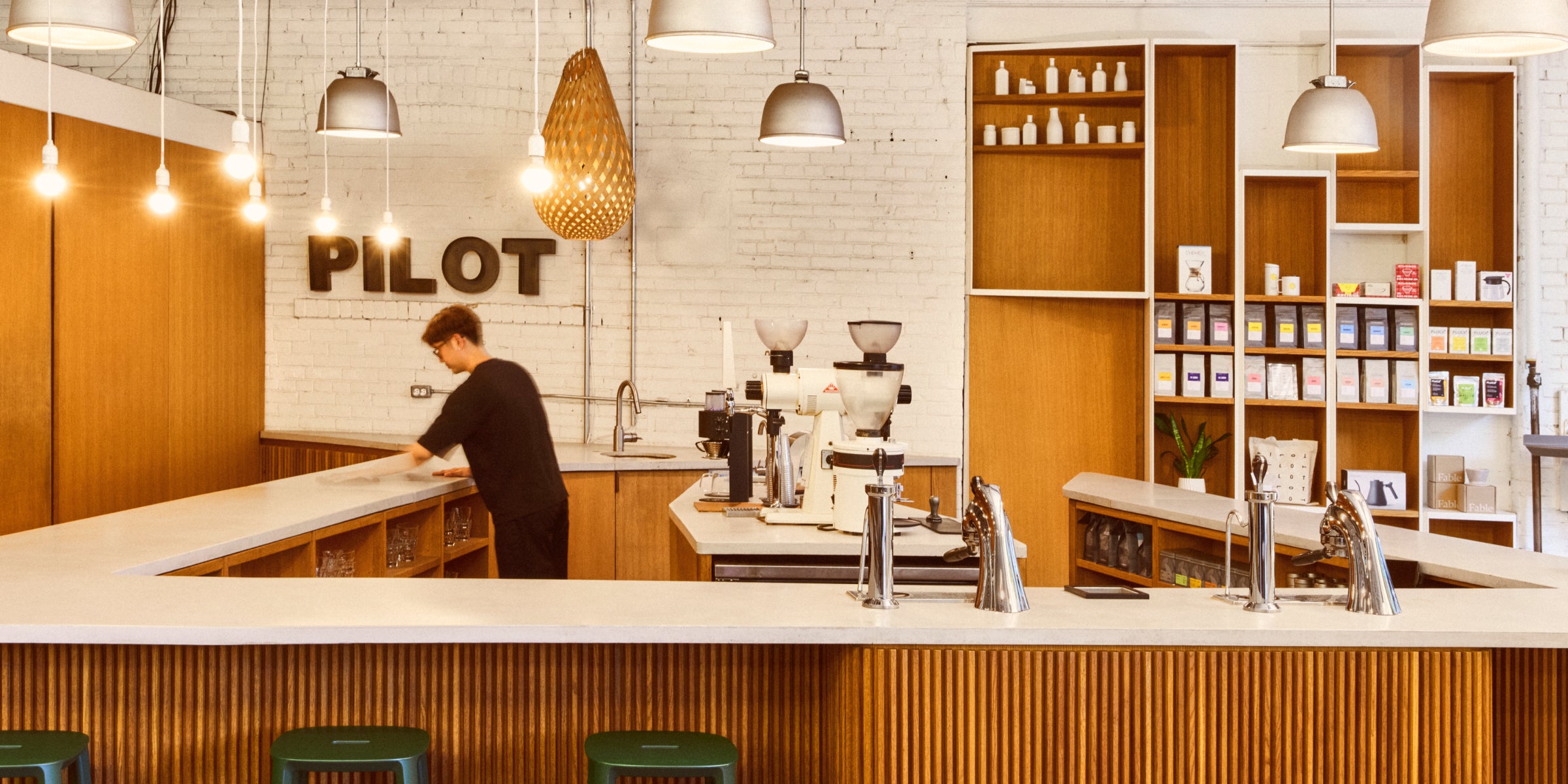 Brightly lit image of the Wagstaff Roastery's Tasting Bar as it currently stands. A barista is at on the right side of the u shaped bar cleaning the bar top