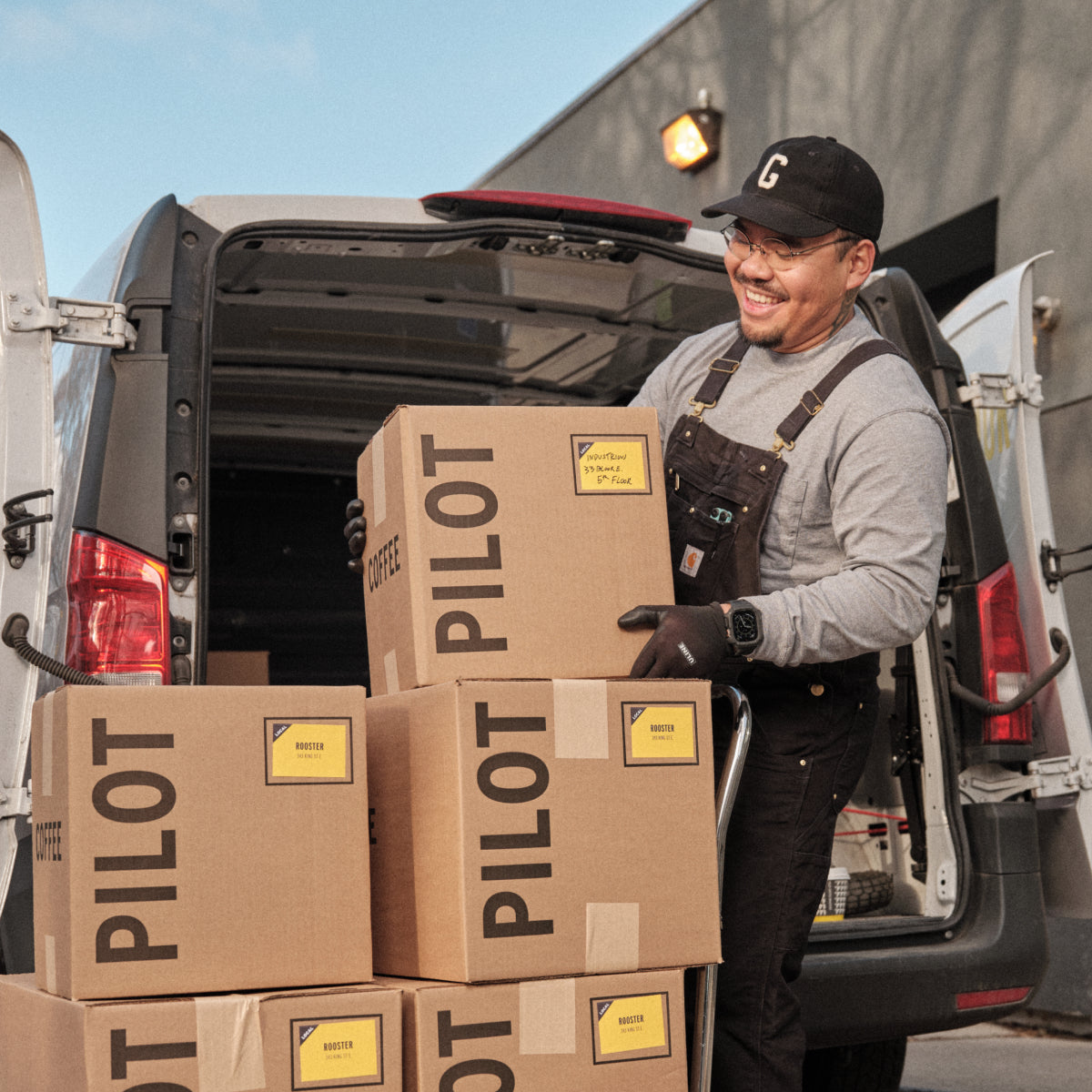 Man loading branded Pilot Coffee boxes into a delivery van in front of the Wagstaff Roastery