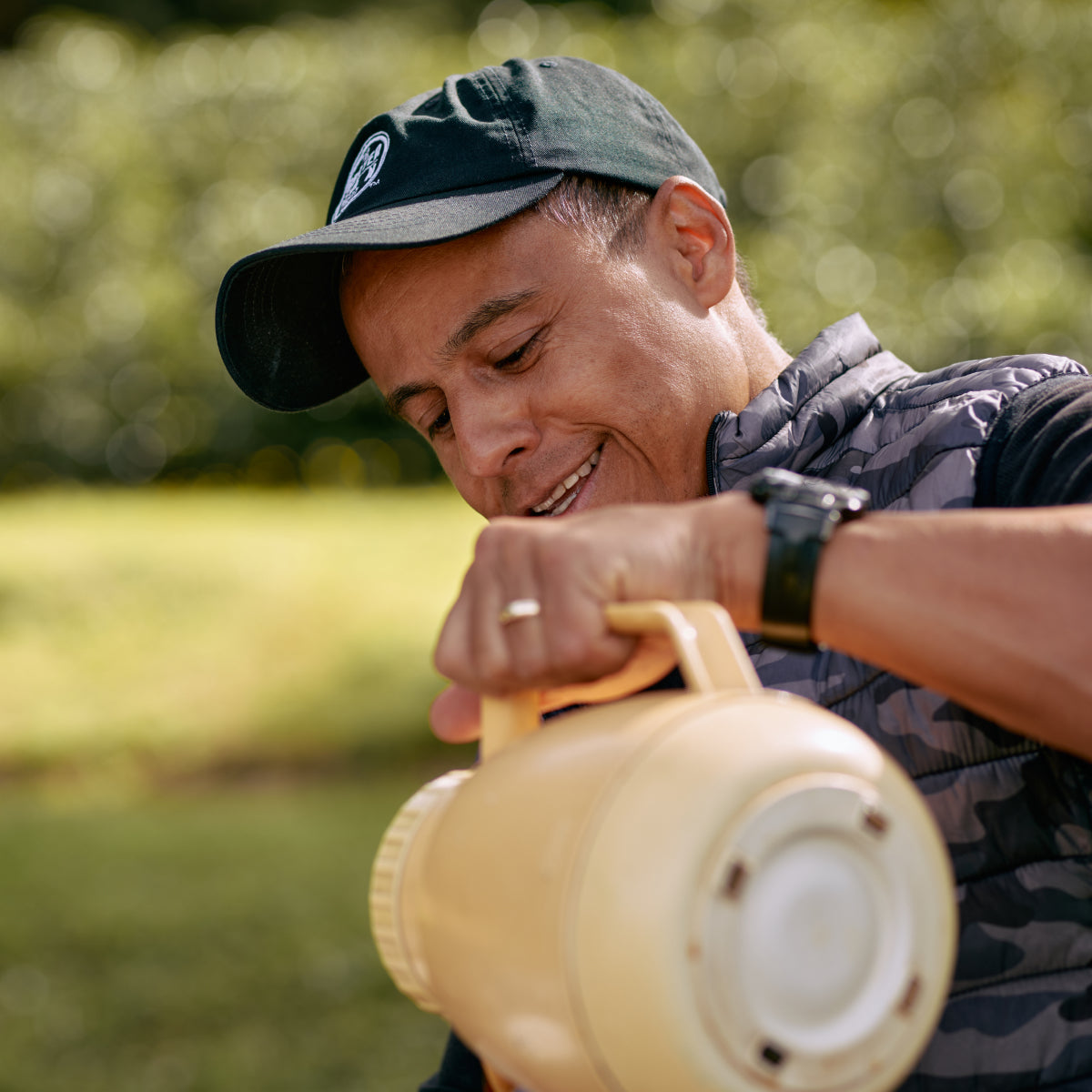 Close up of a man smiling and pouring from a large carafe