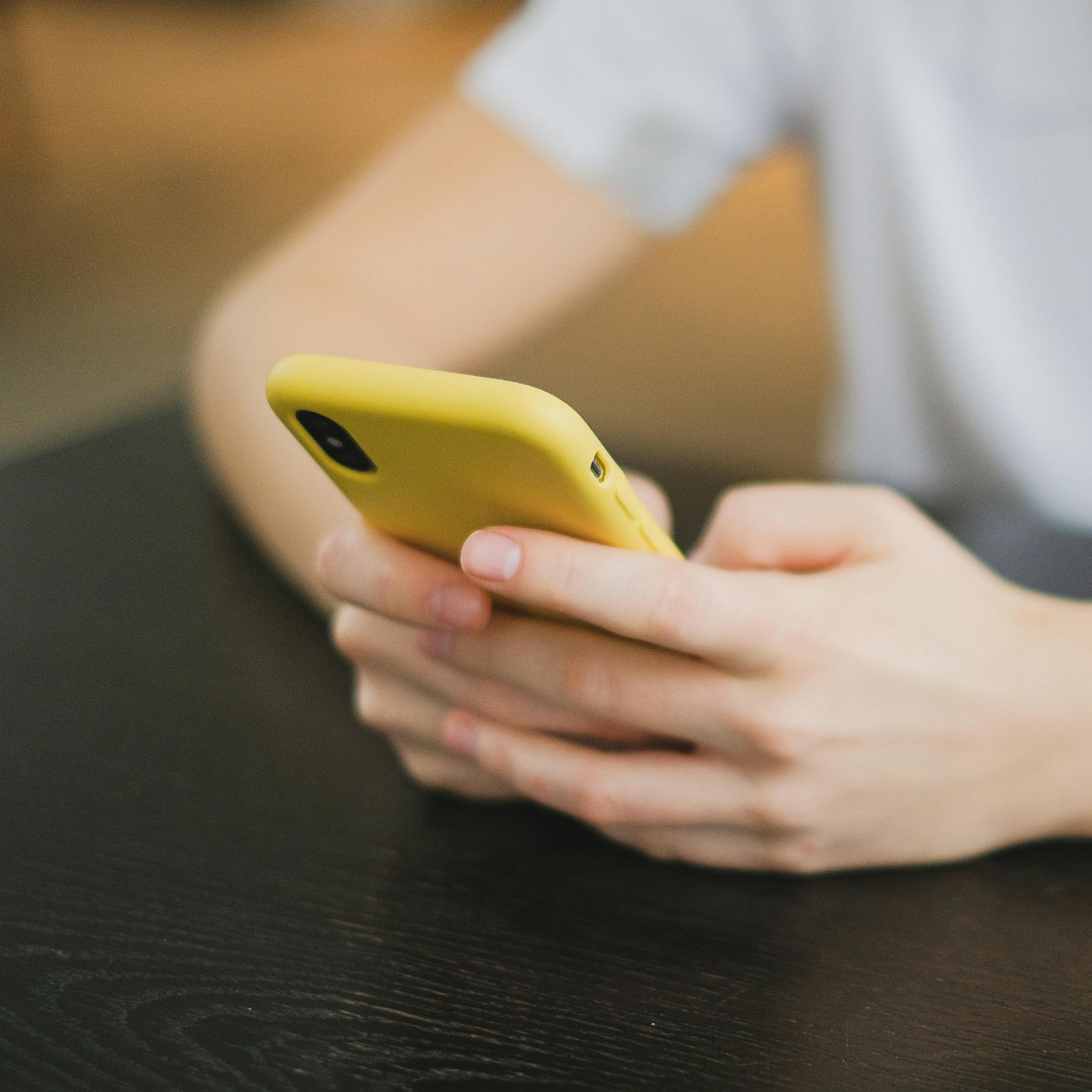 A close up of a person holding their phone while sitting at a table. 