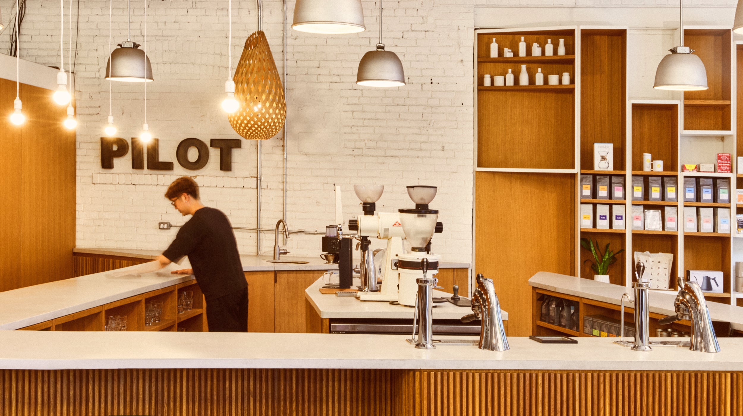 Barista in the brightly lit Wagstaff tasting bar location cleaning the bar top. 